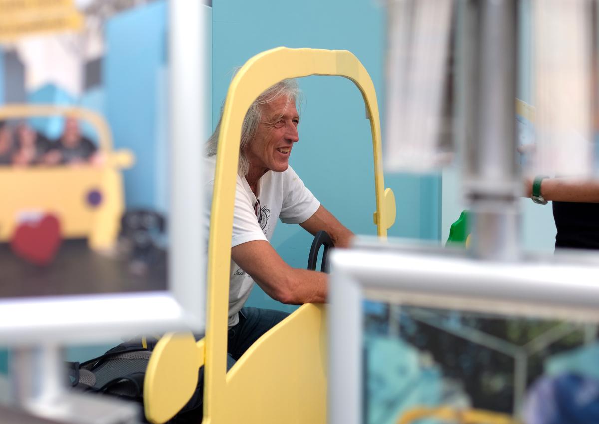 Ein Mann sitzt im Holzauto des Pop-up-Fotostudios